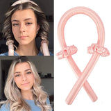 Two women with styled hair and a pink balloon sculpture shaped like a ribbon.