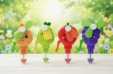 Four colorful cartoon-style fans with fruit designs on a wooden surface and floral background