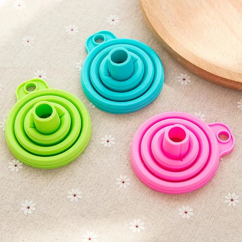 Three colorful silicone dog bowls in green, blue, and pink on a floral fabric background.