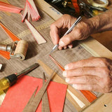 Close-up of hands working with craft materials on a wooden surface