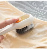 Person using a scrub brush on a piece of fabric with water in the background