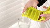 Green ice cube tray with dog treats being used to fill a glass.