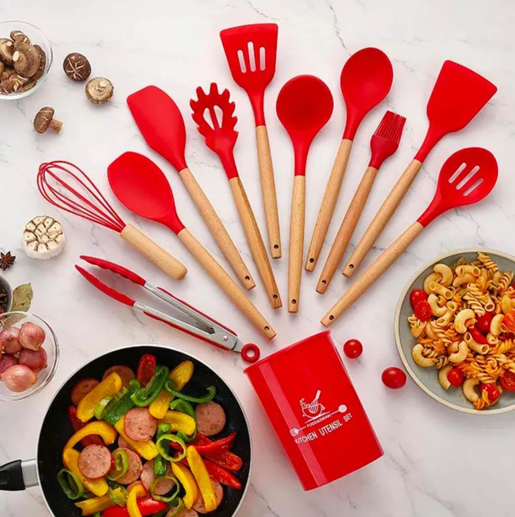 Set of red and beige kitchen utensils on a white surface with food items.