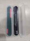A three-piece makeup removal tool set in a clear plastic case, featuring a black nail file on the left, three silver metal picks in the center, and a translucent plastic cover on the right, shown on a light beige textured surface.