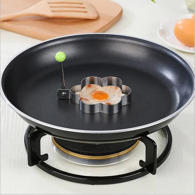Flower-shaped egg mold on a frying pan with an egg inside, on a stove.