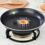Flower-shaped egg mold on a frying pan with an egg inside, on a stove.