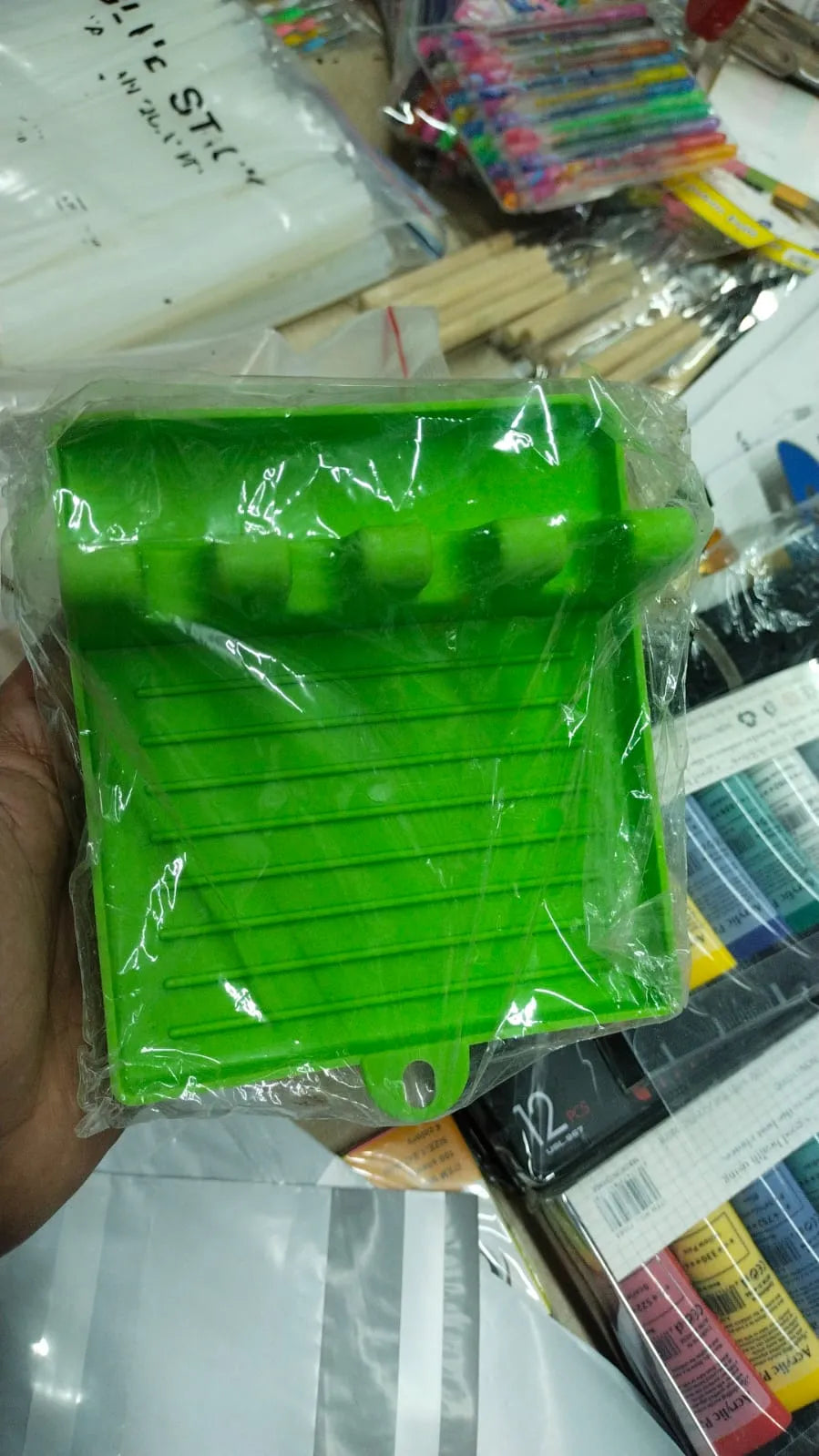 Green plastic tool on a cluttered surface with various items in the background