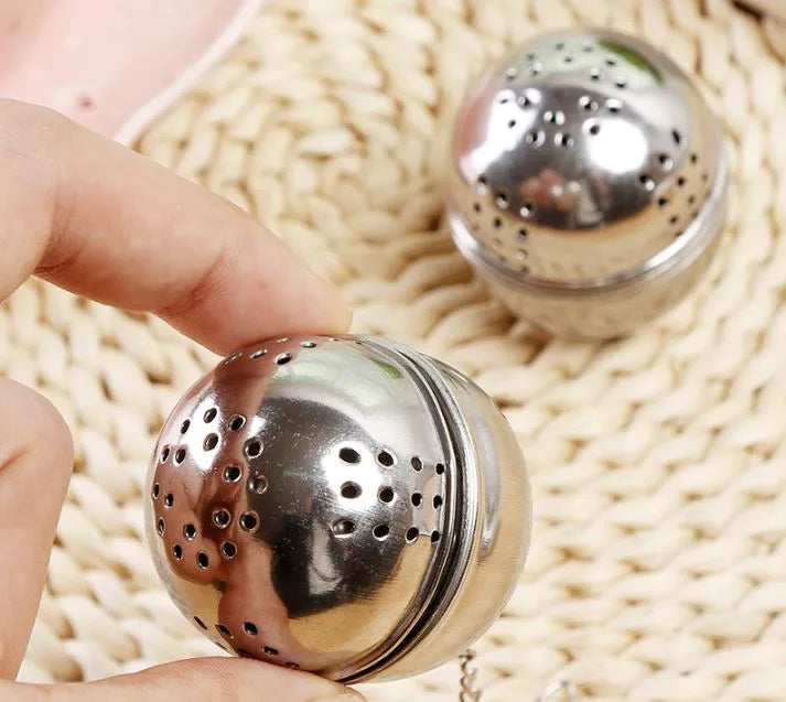 Metallic tea ball infusers on a woven surface
