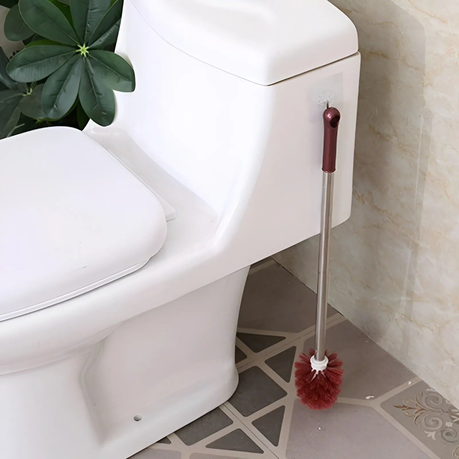 Toilet cleaning brush with red bristle head leaning against a white toilet in a bathroom.