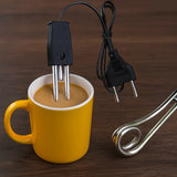 An electric coffee maker insert with a black power cord and metal heating element shown next to a yellow mug filled with coffee on a dark wooden surface.