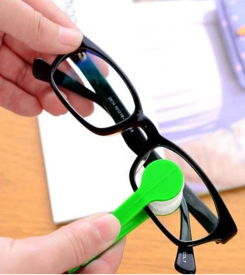 Person cleaning glasses with a green lens cleaner on a wooden surface