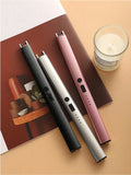 Three electronic devices in black, silver, and pink on a magazine with a candle in the background.