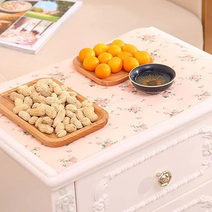Nuts on a wooden tray with oranges and a small bowl on a floral-patterned surface.