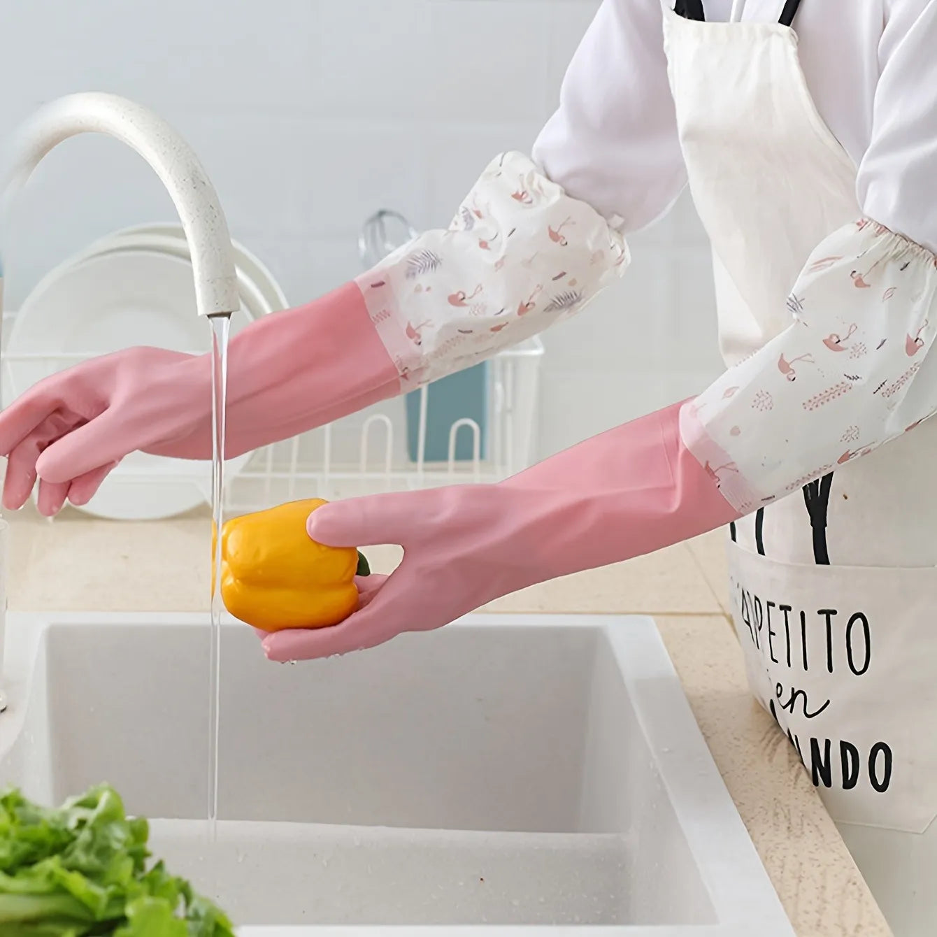 Person washing a yellow pepper in a kitchen sink with pink gloves on.