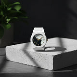White watch with black face on a concrete block with a dark background